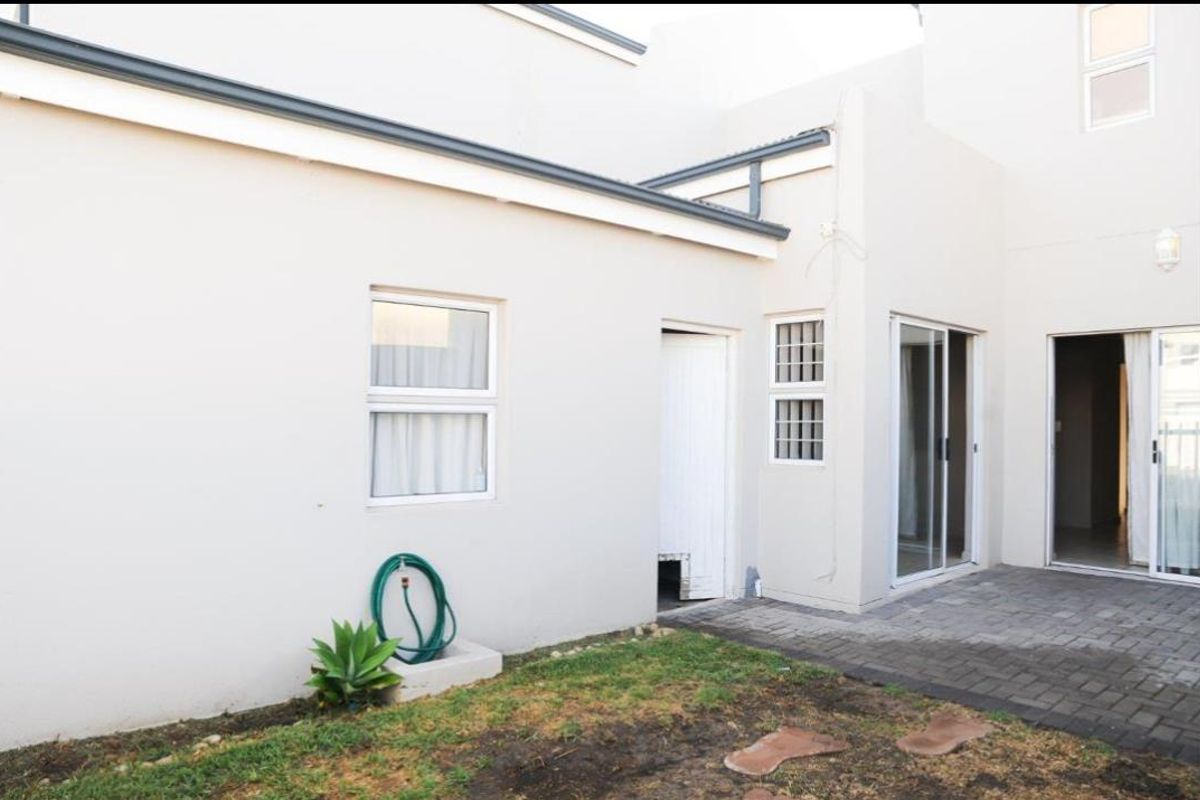 Rear exterior view featuring a paved patio area, sliding glass doors, and access to the main dwelling.