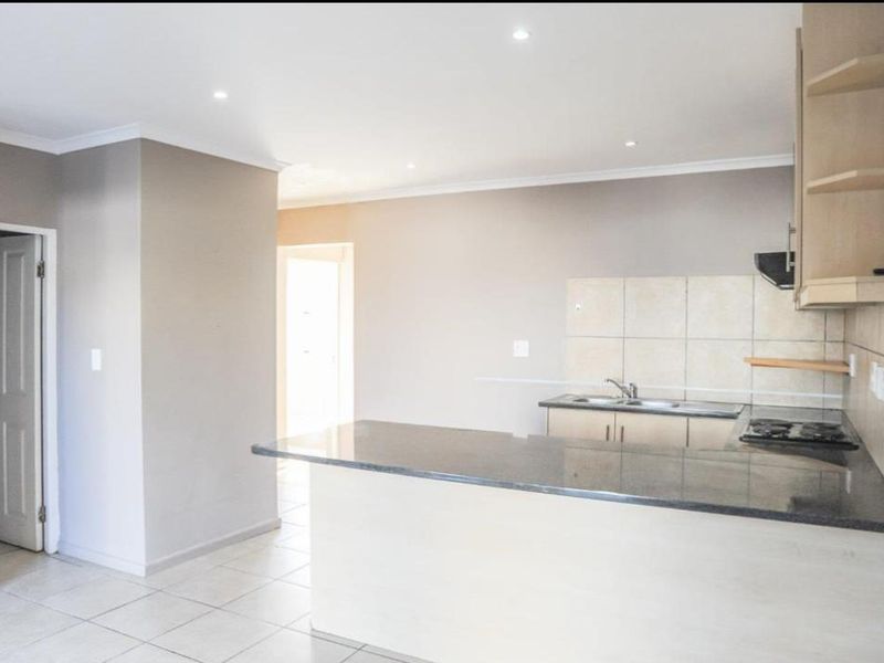 A clean, functional kitchen featuring granite countertops, built-in cabinetry, a tiled backsplash, and a built-in hob with an extractor fan.