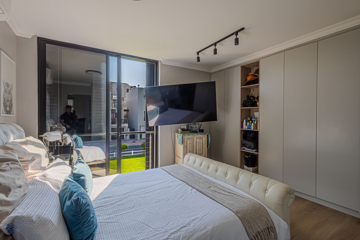 A well-maintained bedroom featuring built-in cupboards, modern track lighting, and a large sliding glass door providing access to an outdoor area.