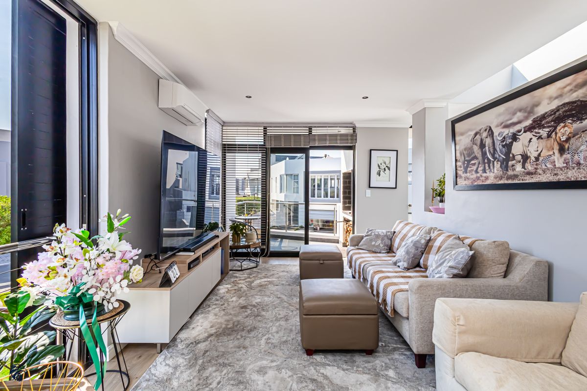 A bright and well-maintained living room featuring neutral tones, recessed lighting, air conditioning, and large sliding glass doors leading to an outdoor area.