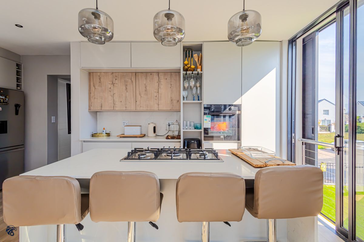 Modern kitchen featuring a central island with a gas hob, sleek built-in cabinetry, and large sliding glass doors providing natural light and outdoor access.
