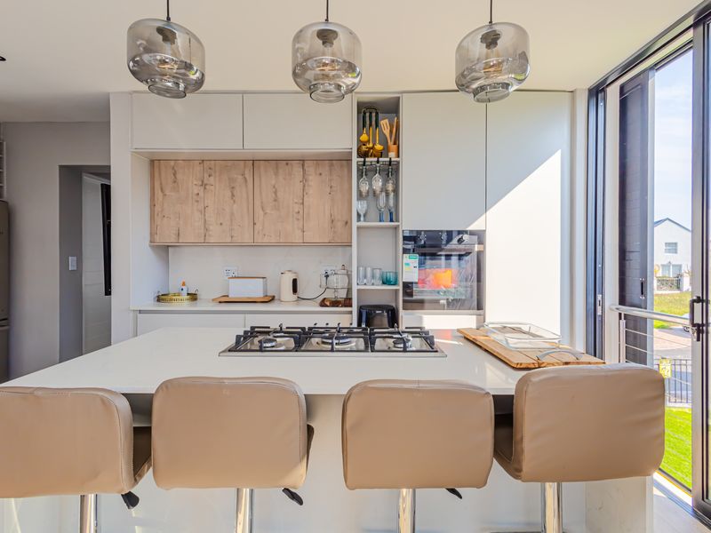 Modern kitchen featuring a central island with a gas hob, sleek built-in cabinetry, and large sliding glass doors providing natural light and outdoor access.