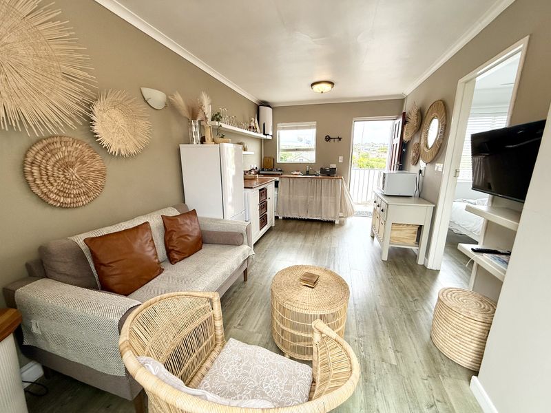 Open-plan living area featuring a compact kitchen with wooden countertops, laminate flooring, and direct access to a balcony.