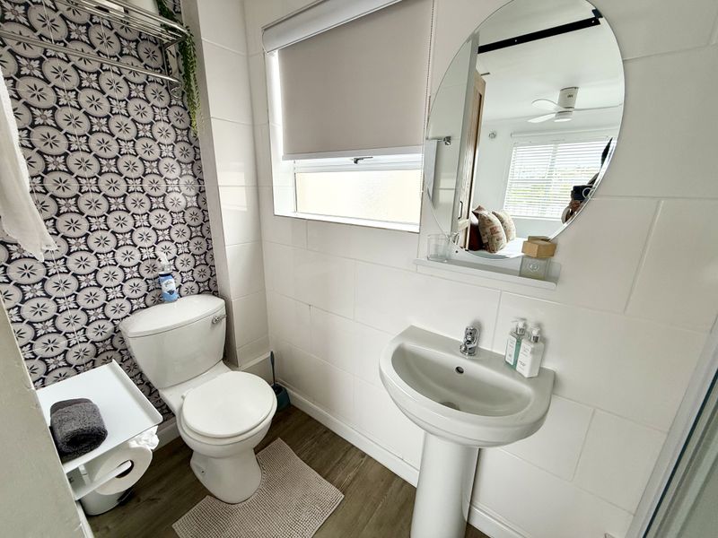 A well-maintained bathroom featuring a pedestal basin, toilet, and a decorative tiled feature wall with modern finishes.