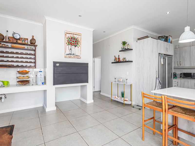 Open-plan living area featuring a modern kitchen with island, built-in braai, tiled flooring, and contemporary cabinetry with integrated appliances.