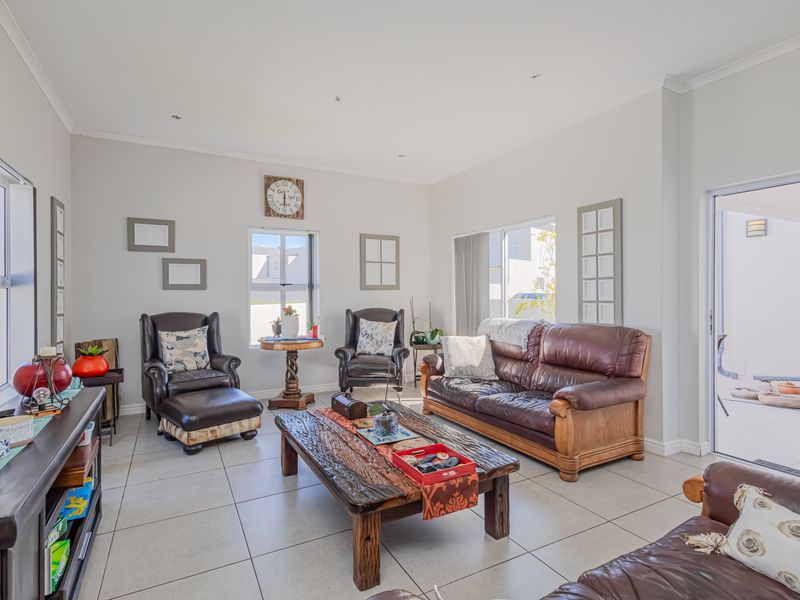 A bright and spacious living room featuring neutral tiled flooring, recessed lighting, and direct access to an outdoor patio area through a sliding glass door.