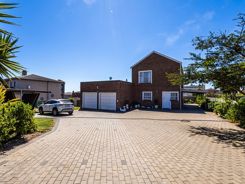 Front elevation of a two-story brick house featuring a spacious paved driveway, double garage, and an attached carport.