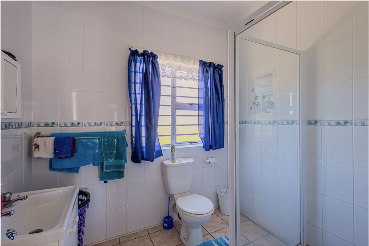 A functional bathroom featuring a shower enclosure, toilet, and washbasin with tiled finishes throughout.