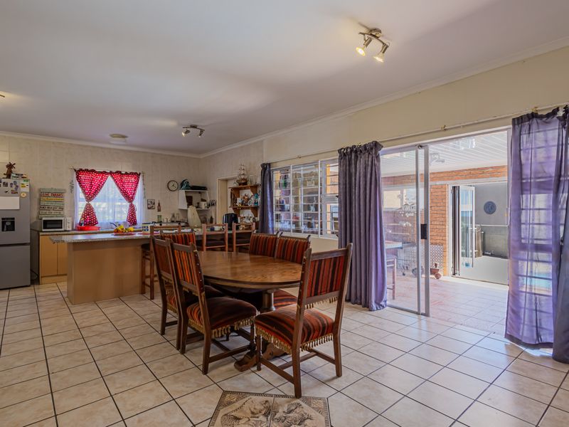 Open plan kitchen and dining area featuring tiled floors, a central kitchen island, and sliding glass doors providing direct access to the outdoor patio.