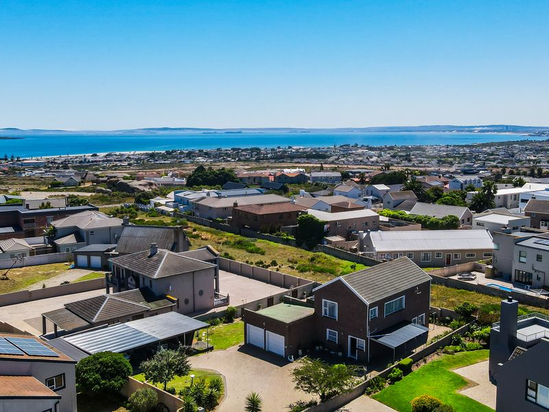 An elevated aerial view of a coastal residential neighborhood, showcasing the property's location, surrounding homes, and proximity to the ocean.