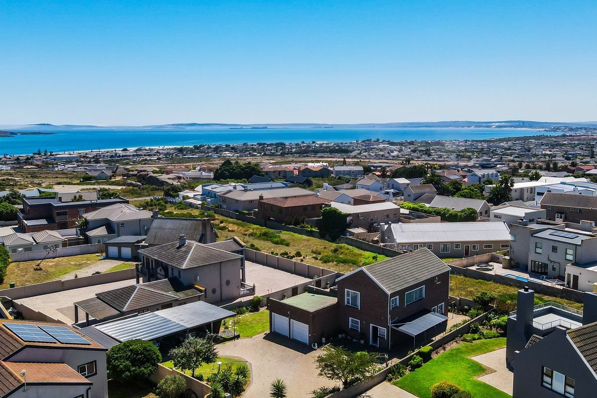 An elevated aerial view of a coastal residential neighborhood, showcasing the property's location, surrounding homes, and proximity to the ocean.