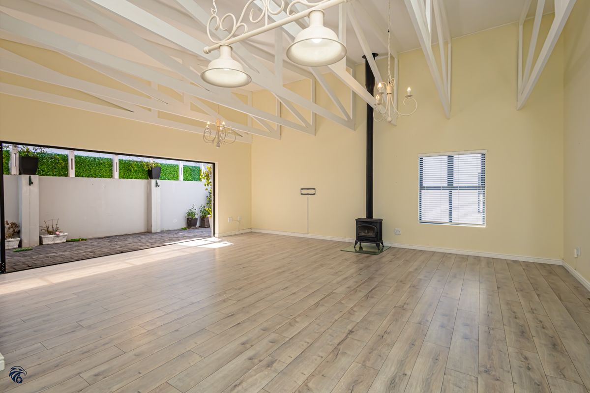Spacious living area featuring high vaulted ceilings with exposed trusses, a freestanding fireplace, and large sliding doors opening to an outdoor patio.