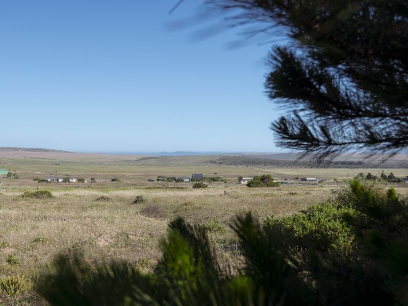 Expansive rural landscape view overlooking the farm property and surrounding countryside under a clear blue sky.