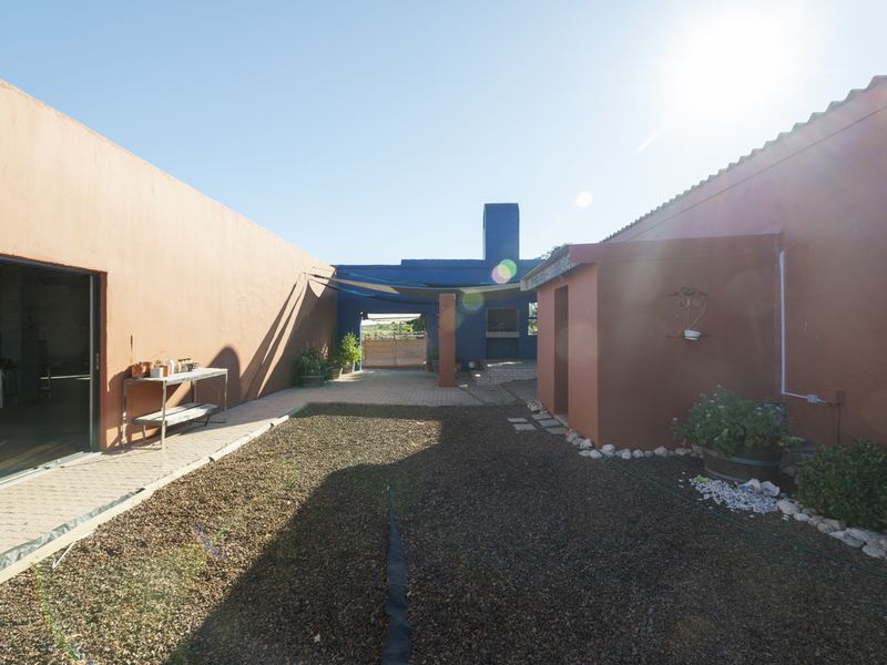 A spacious rear courtyard featuring a built-in braai area, paved surfaces, and direct access to the main dwelling via a sliding door.