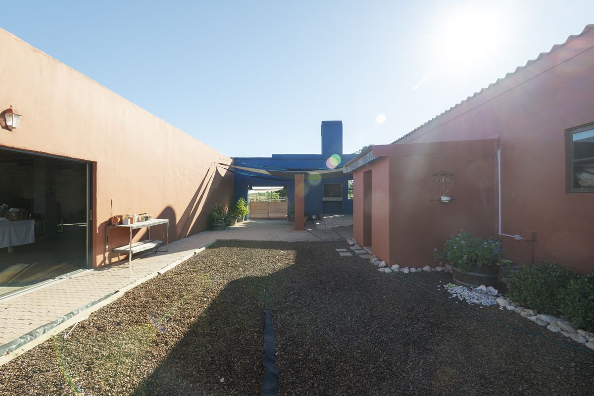 A spacious rear courtyard featuring a built-in braai area, paved surfaces, and direct access to the main dwelling via a sliding door.