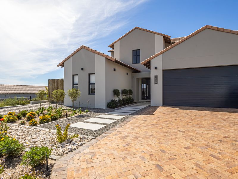 Modern front elevation featuring a paved driveway, double garage, and a well-maintained landscaped garden with a stone pathway leading to the entrance.