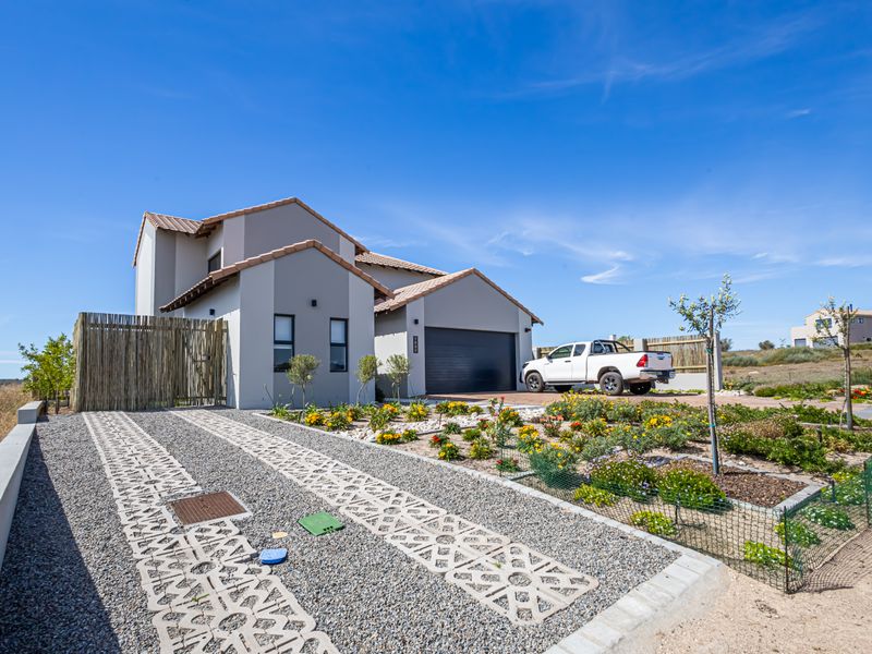 A modern double-story residential home featuring a tiled roof, integrated garage, and a landscaped front garden with a gravel driveway.