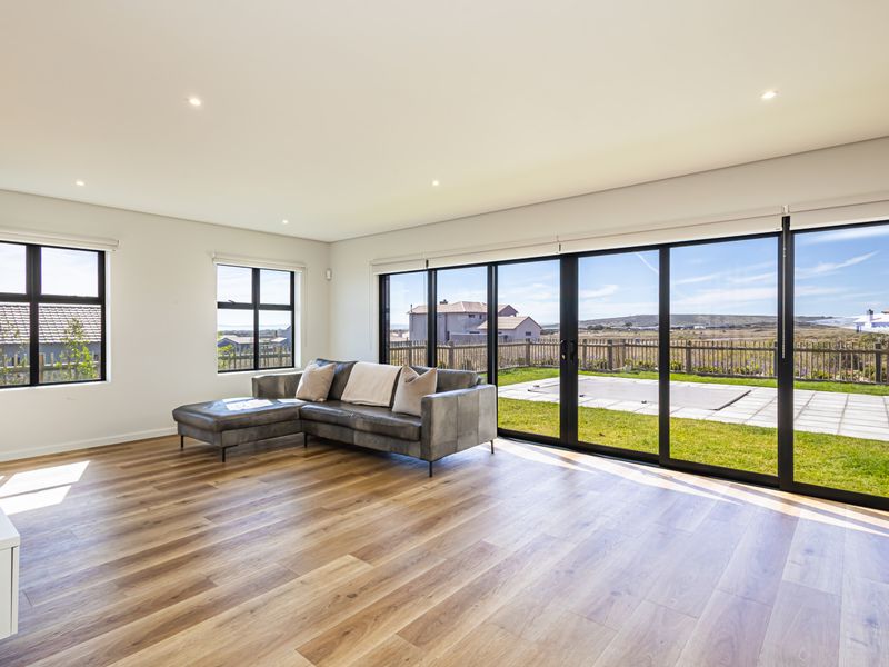 Spacious living room featuring modern laminate flooring, recessed lighting, and large black aluminium sliding doors providing seamless access to the garden and patio area.