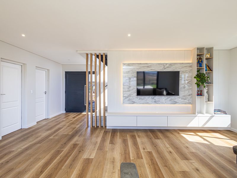 Modern living room featuring a sophisticated marble-look media wall with integrated shelving, recessed LED lighting, and high-quality timber flooring.