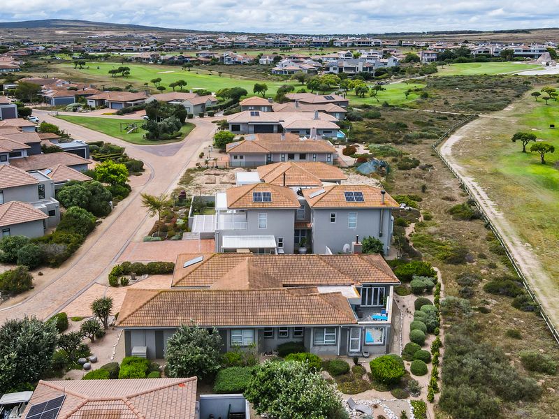 Aerial view of a residential property featuring a tiled roof, solar panels, a private swimming pool, and a landscaped garden within a golf estate.