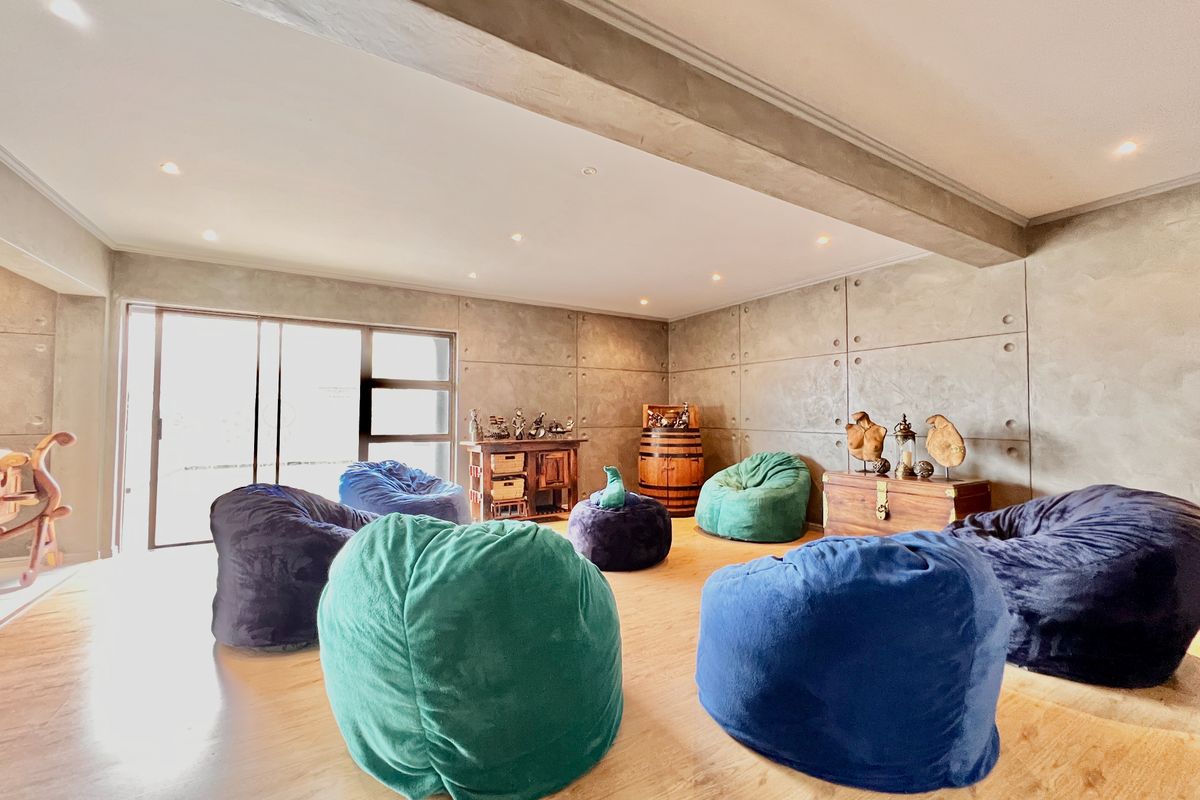 Spacious living area featuring industrial-style concrete panel walls, recessed ceiling lighting, and large sliding glass doors providing natural light and outdoor access.