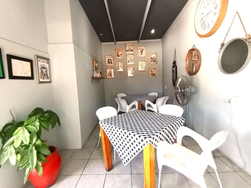 A dining area featuring tiled flooring and a dark recessed ceiling, currently set up with multiple tables and chairs.