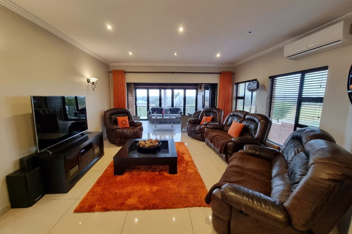 Spacious living room featuring tiled flooring, recessed downlighting, wall-mounted air conditioning unit, and large sliding doors opening to an outdoor patio area.