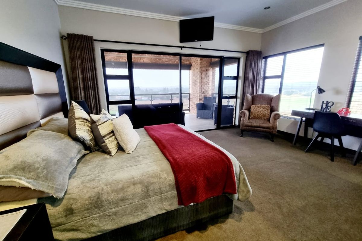 Spacious bedroom featuring large sliding glass doors that open onto a private balcony with scenic views, complemented by neutral carpeting and recessed lighting.