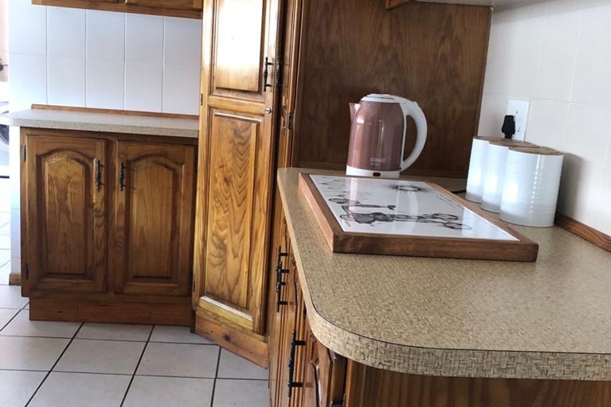 A traditional kitchen featuring wooden cabinetry, laminate countertops, and ceramic floor tiles, offering a functional layout with classic finishes.