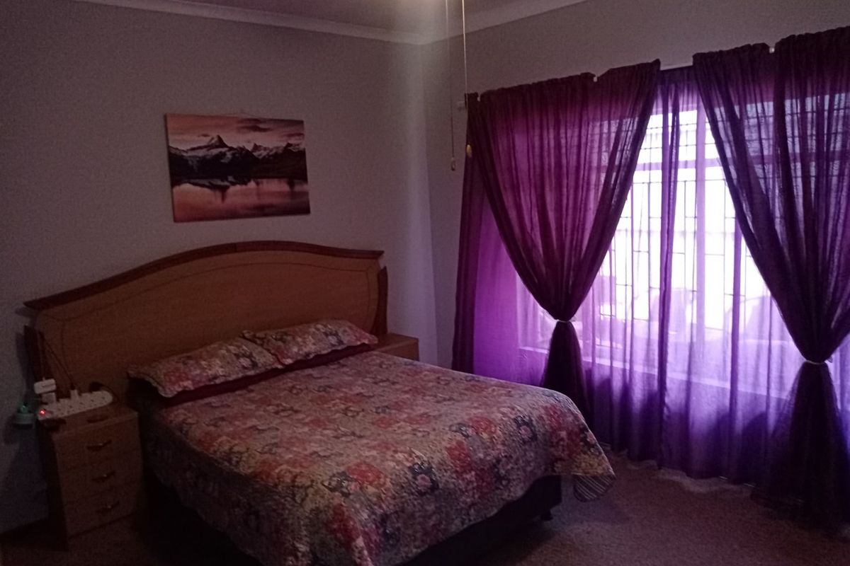 A bedroom featuring a ceiling fan, security bars on the window, and decorative cove cornicing.
