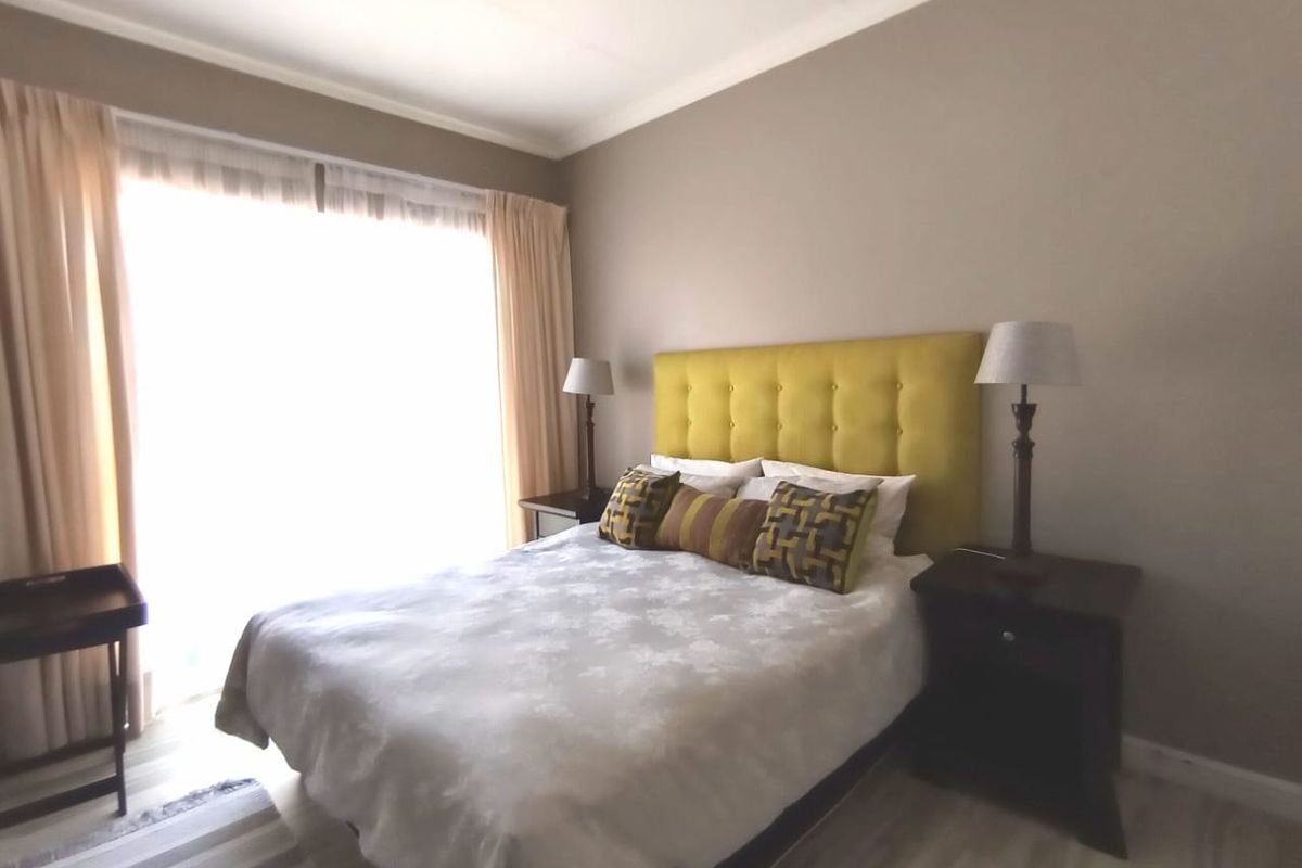 A well-lit bedroom featuring neutral wall tones, crown molding, and large sliding glass doors providing ample natural light.