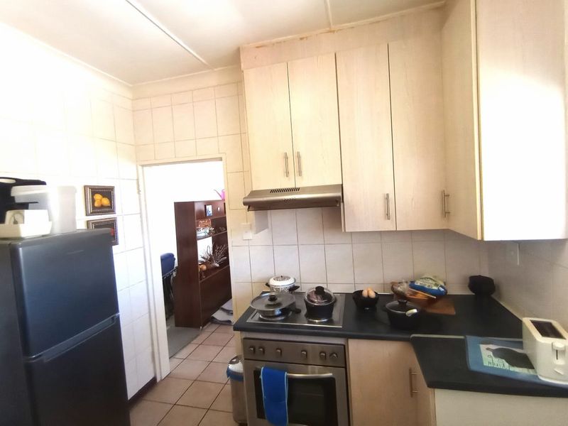 A functional kitchen featuring light-toned built-in cabinetry, a stainless steel extractor fan, a built-in oven with hob, and tiled splashbacks.