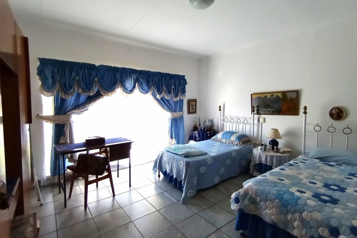 A spacious bedroom featuring tiled flooring and a large sliding glass door that provides ample natural light.