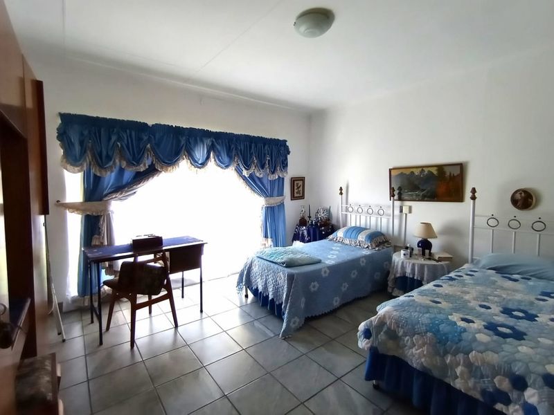 A spacious bedroom featuring tiled flooring and a large sliding glass door that provides ample natural light.