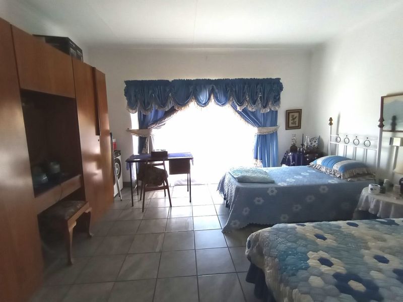 Spacious bedroom featuring tiled flooring, a large built-in wardrobe, and a sliding glass door providing access to the exterior.
