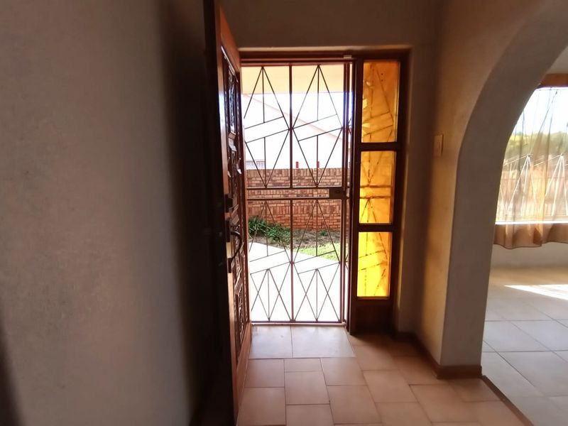 Entrance area featuring tiled flooring, a decorative security gate, and a distinctive stained glass sidelight, leading into an open-plan living space.