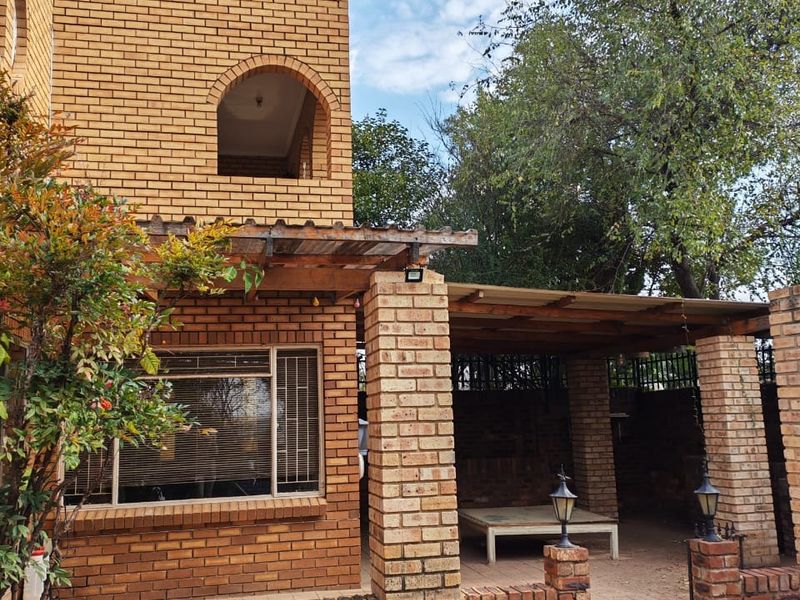 Rear exterior view featuring a face brick facade, a covered timber pergola patio area, and paved outdoor space.