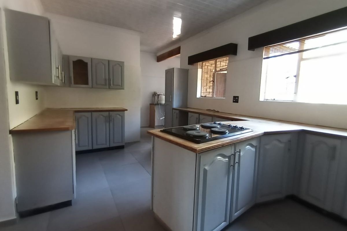 Spacious kitchen featuring grey built-in cabinetry, wooden countertops, and an integrated electric hob, offering a functional layout ready for modern updates.