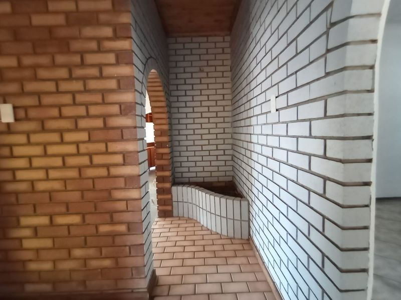 A transitional hallway featuring distinctive brick archways, exposed brick wall finishes, and a built-in brick planter box.
