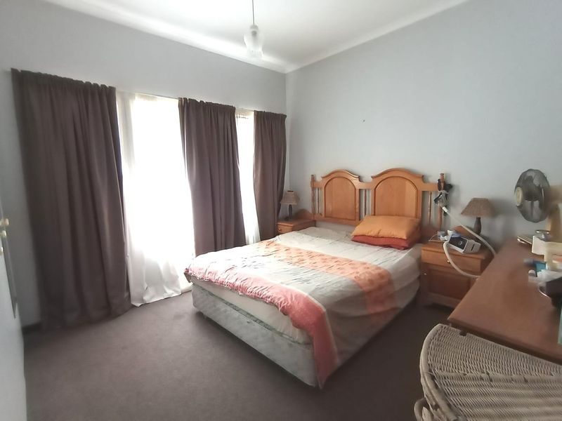 A standard bedroom featuring carpeted flooring and large windows with curtain tracks, offering a functional and lived-in space.