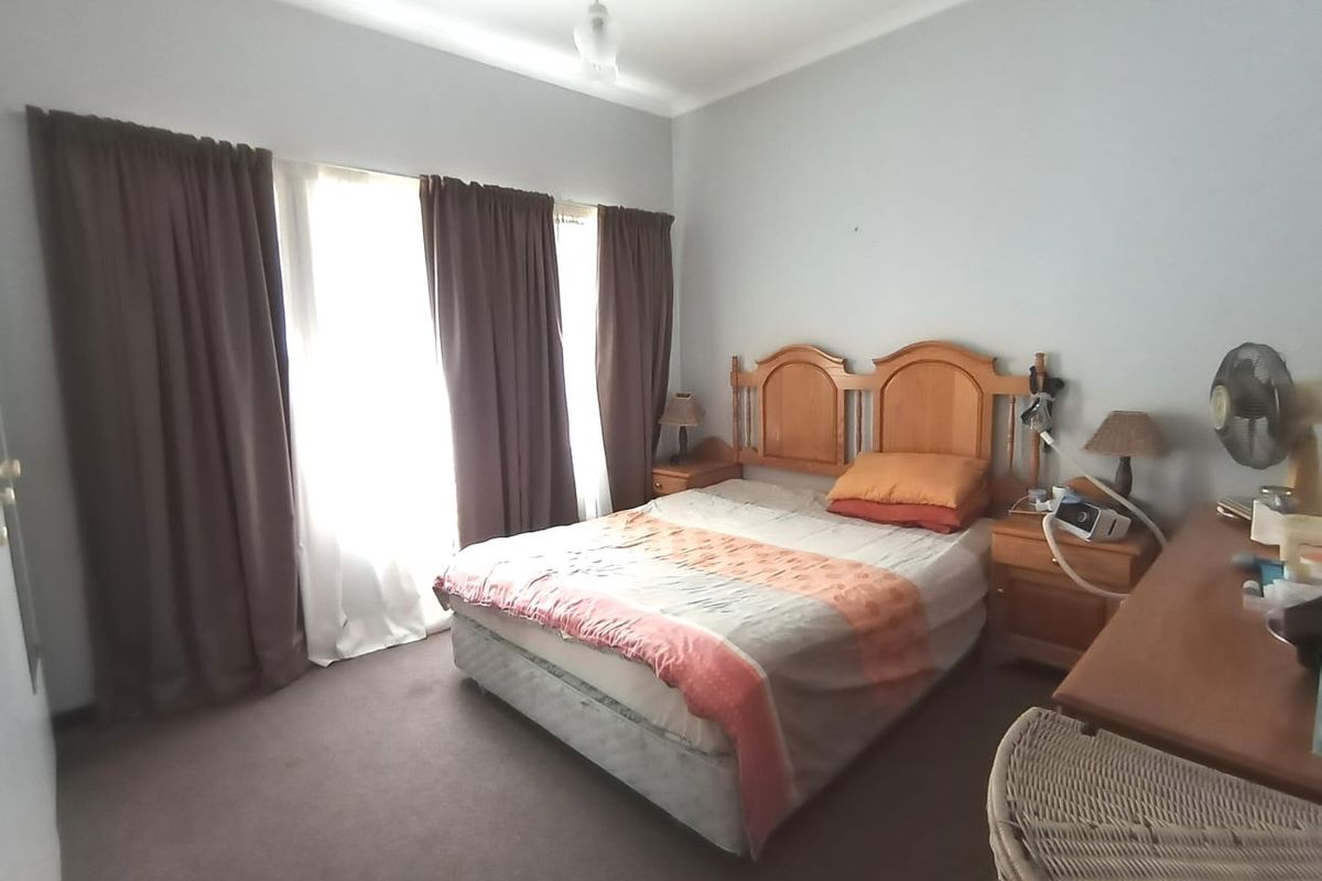A standard bedroom featuring carpeted flooring and large windows with curtain tracks, offering a functional and lived-in space.