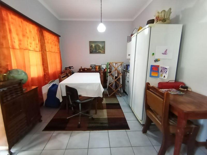 A functional dining room featuring tiled flooring and central pendant lighting, offering a versatile space for family meals.