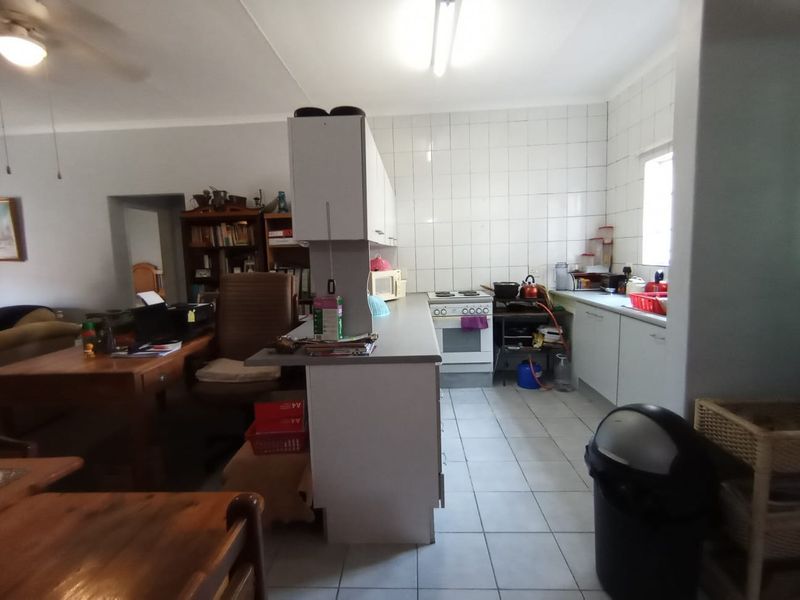 Open-plan kitchen area featuring tiled flooring, white cabinetry, and a tiled splashback, offering a functional layout ready for modern updates.