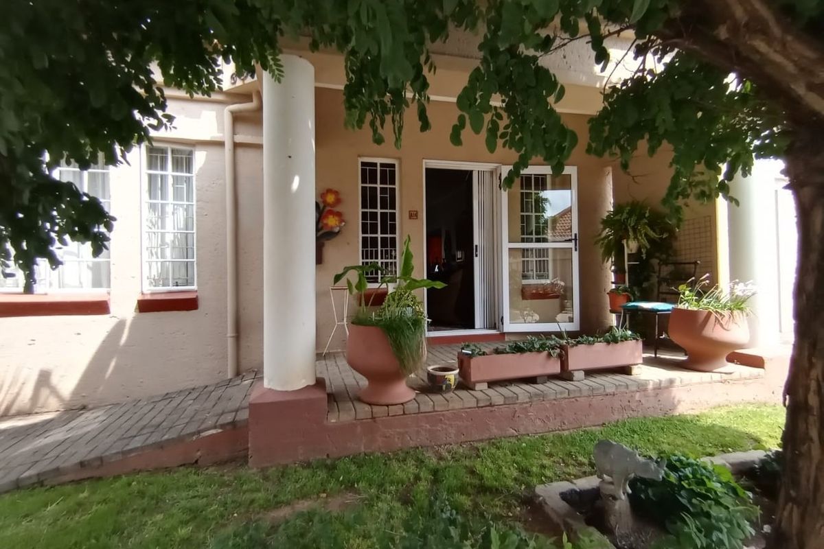 Front entrance of the townhouse featuring a covered porch, concrete columns, and a paved access ramp with security gates and bars.