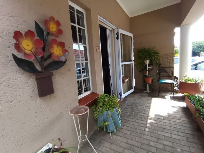 A covered patio area featuring paved flooring, a security gate, and window access, providing a functional outdoor transition space for the townhouse.