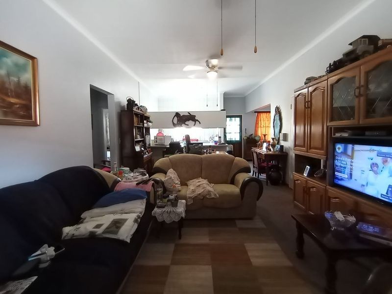 Open plan living area featuring a central ceiling fan and a view through to the kitchen space.