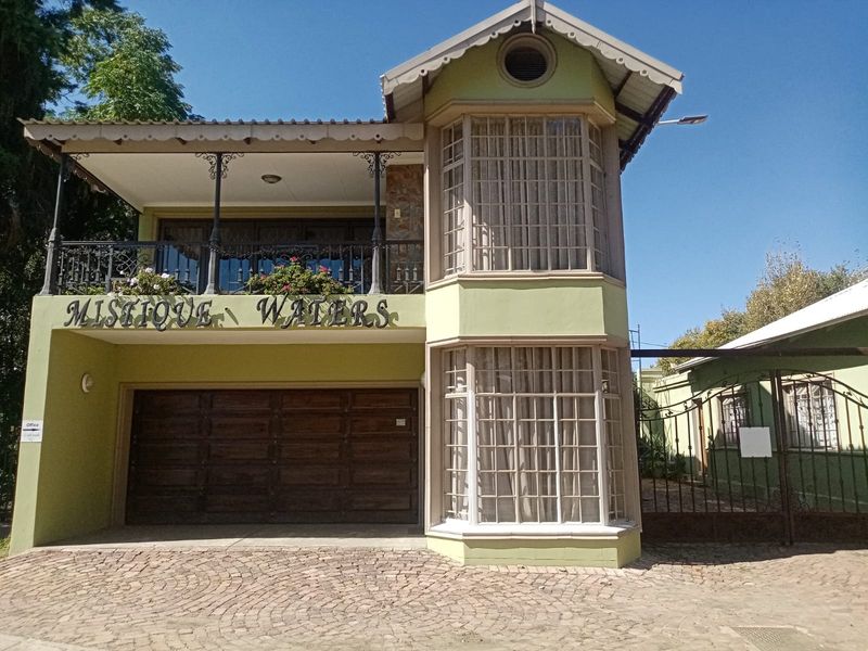 Front facade of a two-story house featuring a double garage, a covered balcony with wrought iron detailing, and a prominent bay window.