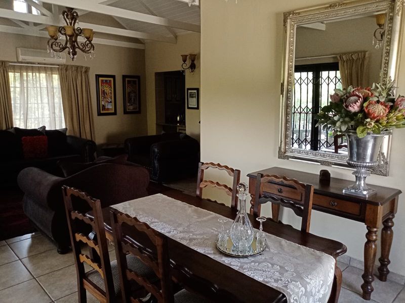Open-plan living and dining area featuring vaulted ceilings with exposed beams, tiled flooring, and a split-system air conditioner.