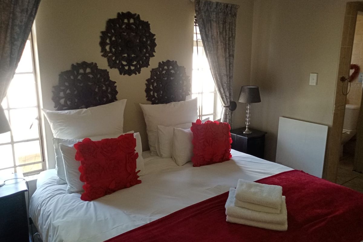 A bedroom featuring natural light from dual windows and an adjoining ensuite bathroom.