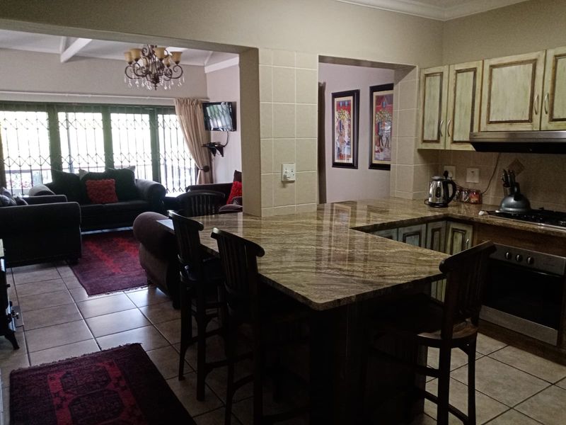 Open-plan kitchen and living area featuring granite countertops, built-in cabinetry, and tiled flooring, creating a functional and connected living space.